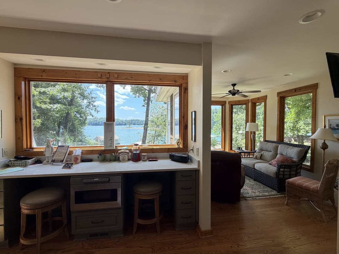 Great room with vaulted wood-beam ceiling, floor-to-ceiling windows, and lake views
