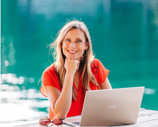 Ashley Smith working on a laptop at a lakeside table
