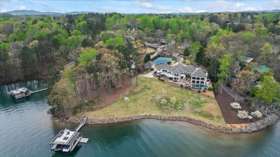 Aerial view of a lakefront estate with pool, tennis court and private docks