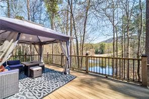 Backyard deck with a canopy gazebo overlooking a pond and trees
