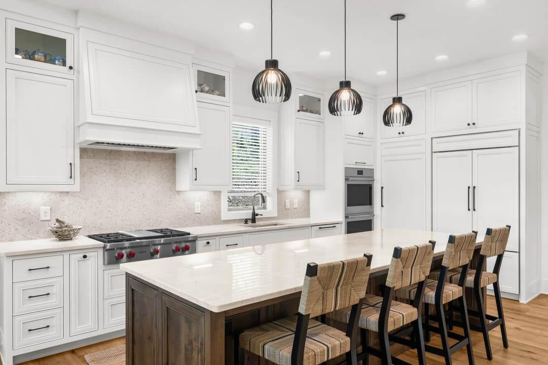 Kitchen with white cabinetry, oversized island, and stainless steel appliances
