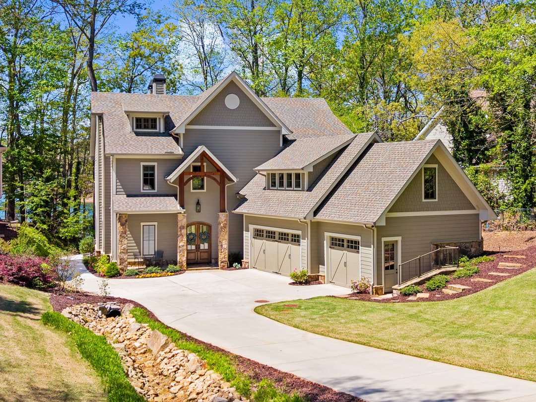 Drone view of the home with covered upper terraces and lakeside outdoor living