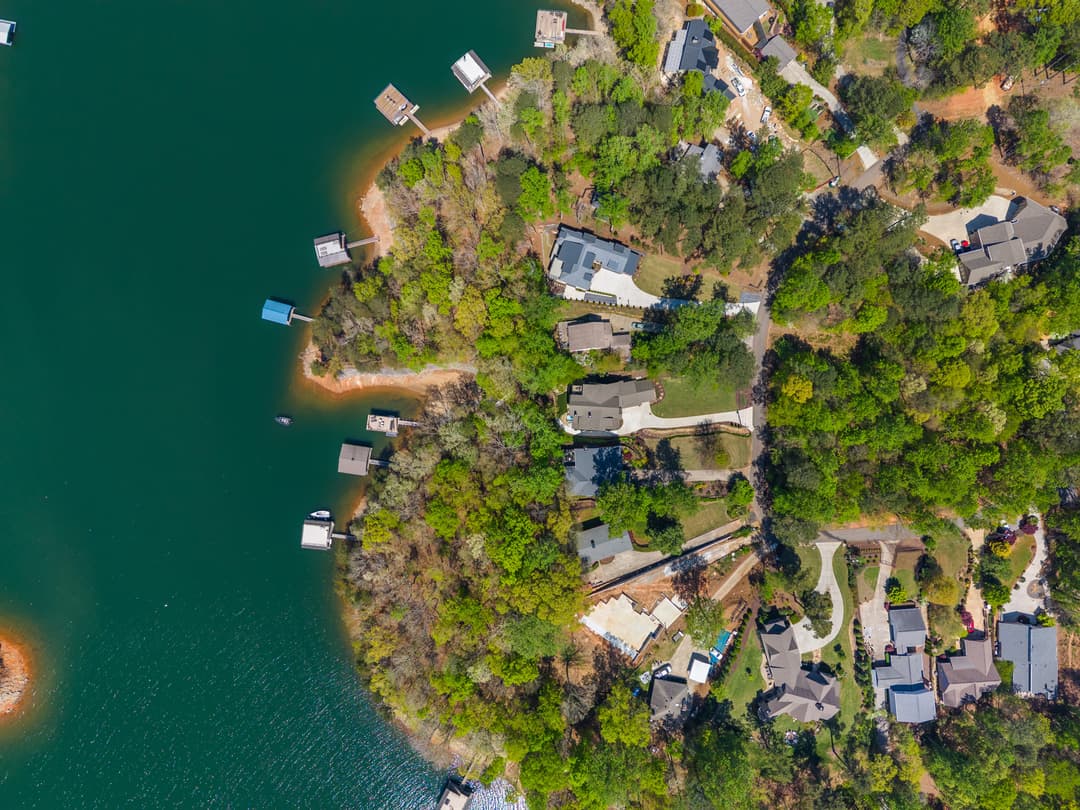 High-angle drone shot of the lake home, lawn, and dock