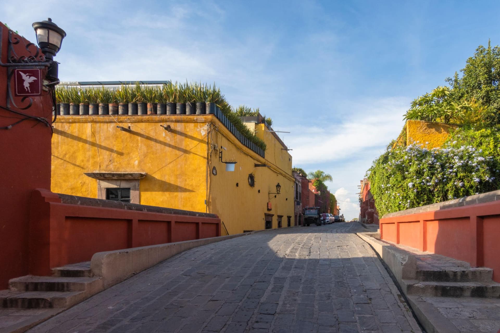 Yellow and red colonial walls beside a cobblestone lane in San Miguel de Allende